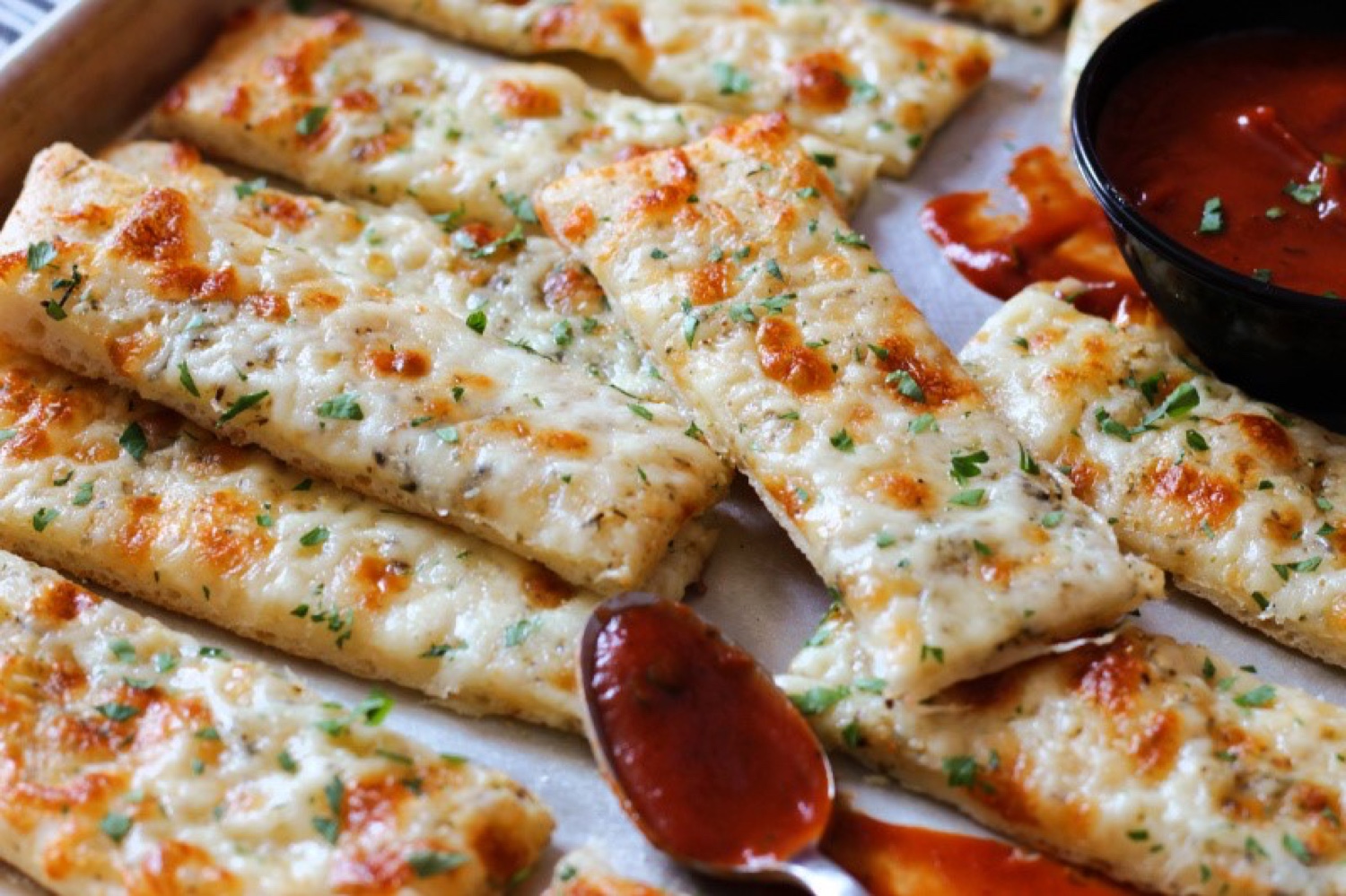 Cheesy garlic bread sticks with melted mozzarella, herbs, and marinara dipping sauce