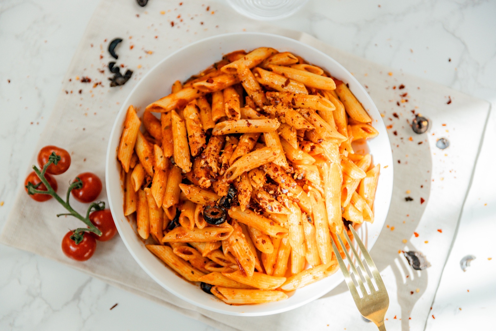 A bowl of penne in red sauce with cherry tomatoes on the side — Pastaphony Glendora signature